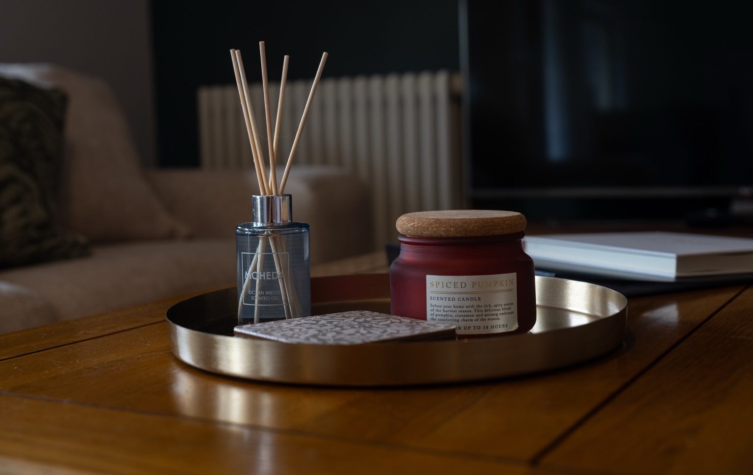 Scented candle and diffuser arranged on a brass tray